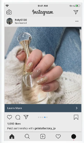 Náhled sponzorované reklamy na Instagramu na mobilu – detail ruky s nehty zdobenými třpytivým lakem a tlačítko Learn More.